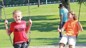 Star Photo/Curtis Carden Two youngsters enjoy some time on the swings Friday morning at Cat Island Park.